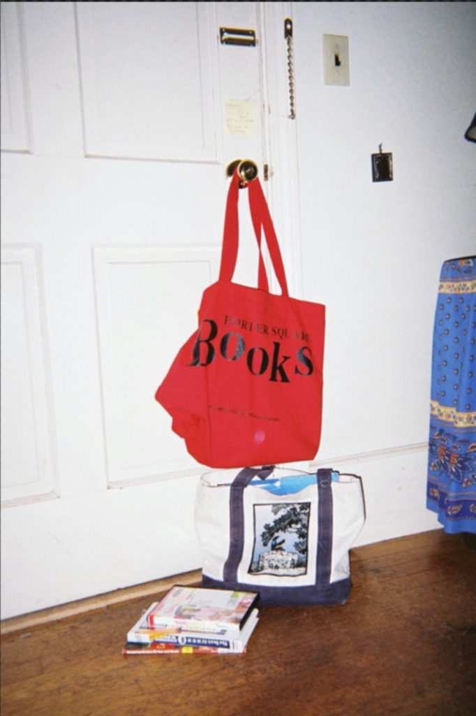 A door with a red bag, a white bag, and some movies nearby