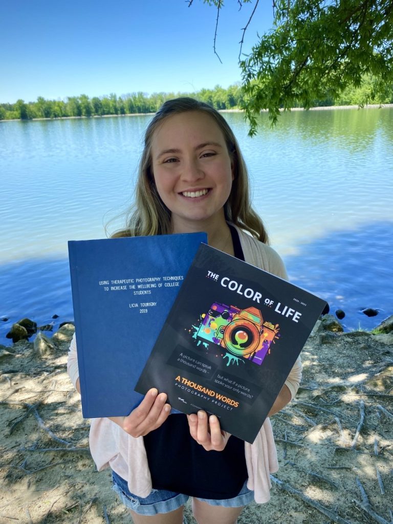 Lee Anne Tourigny holding two books by the water