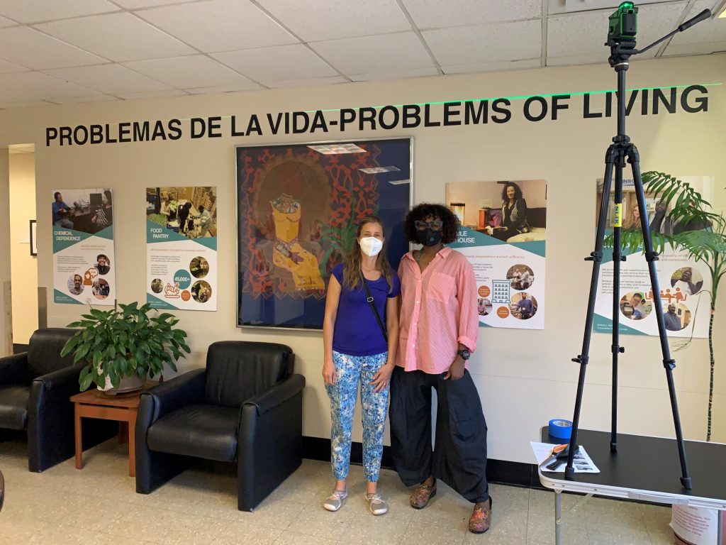 Dr. Chrisann Newransky and Shelita Birchett Benash stand in front of the photovoice cafe instillation