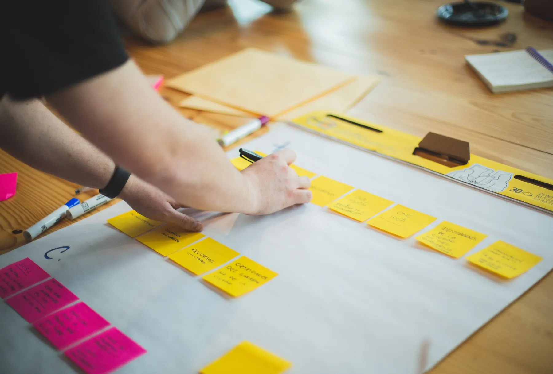 Individual adding notes to sticky notes on a flip chart