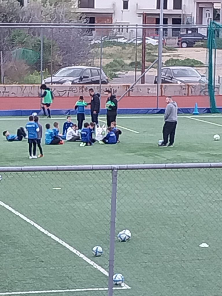 Several soccer players gathered and sitting on the grass during a break on the field