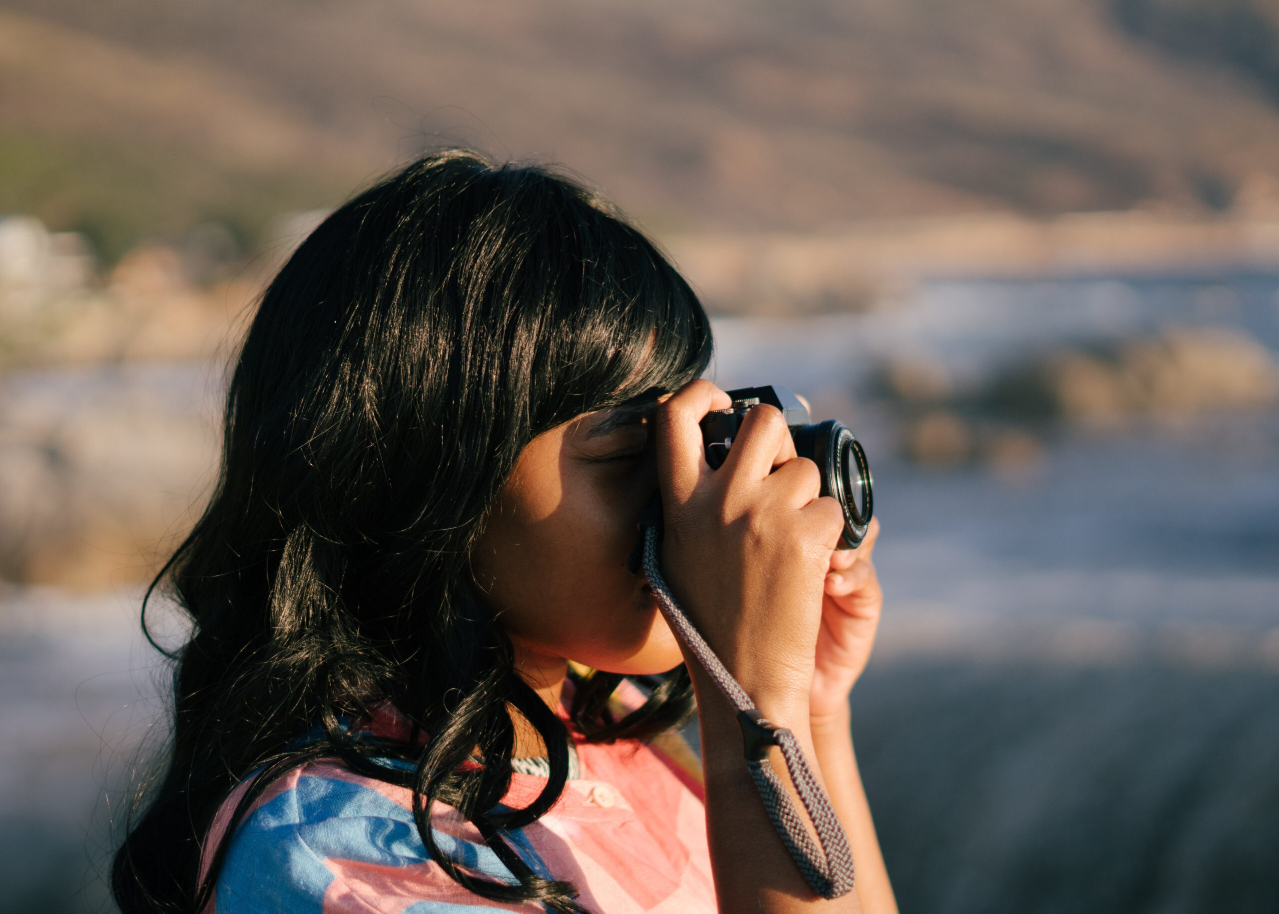 A girl in focus taking a picture with a camera