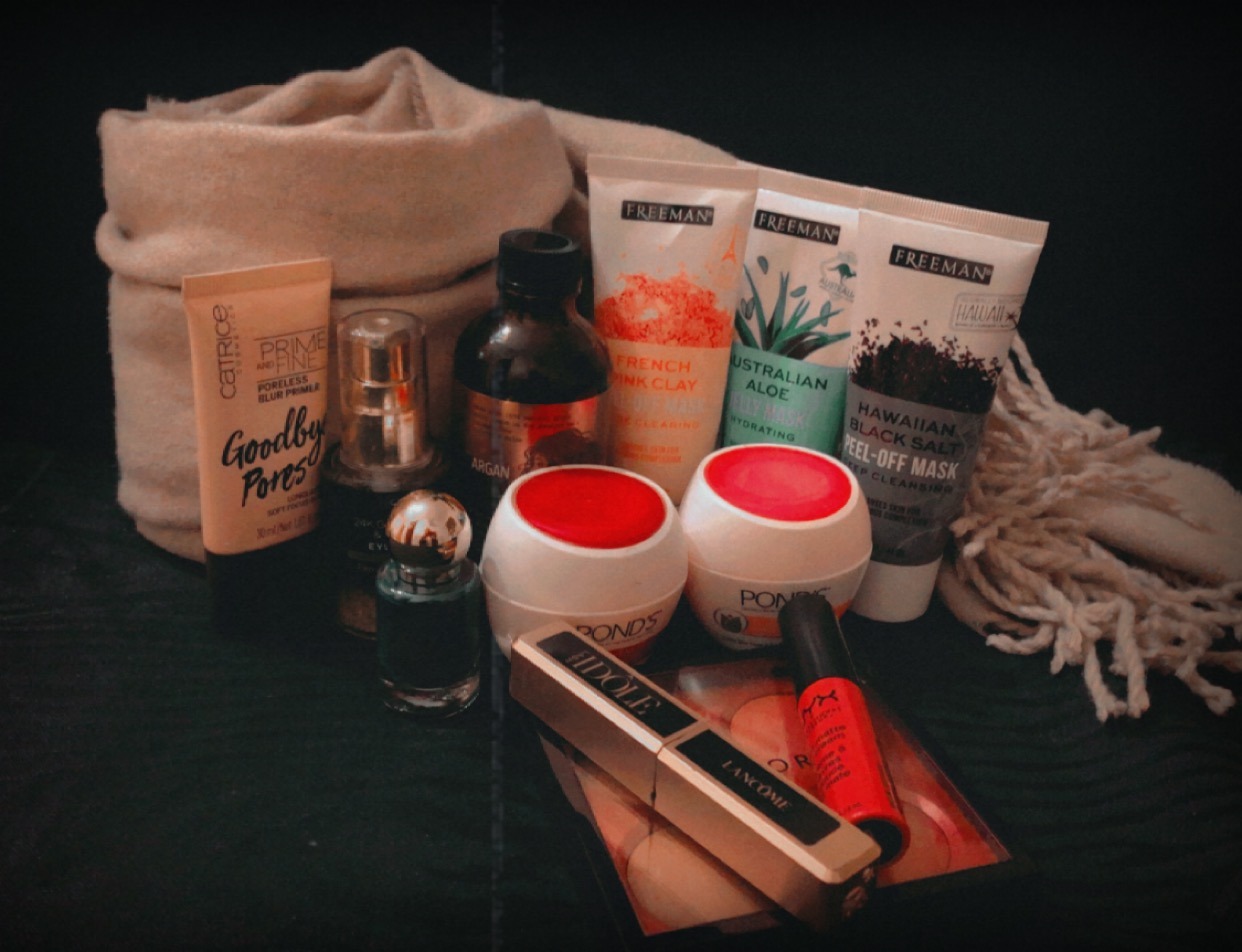 Different skin care products leaning against a bag and laying on a black background