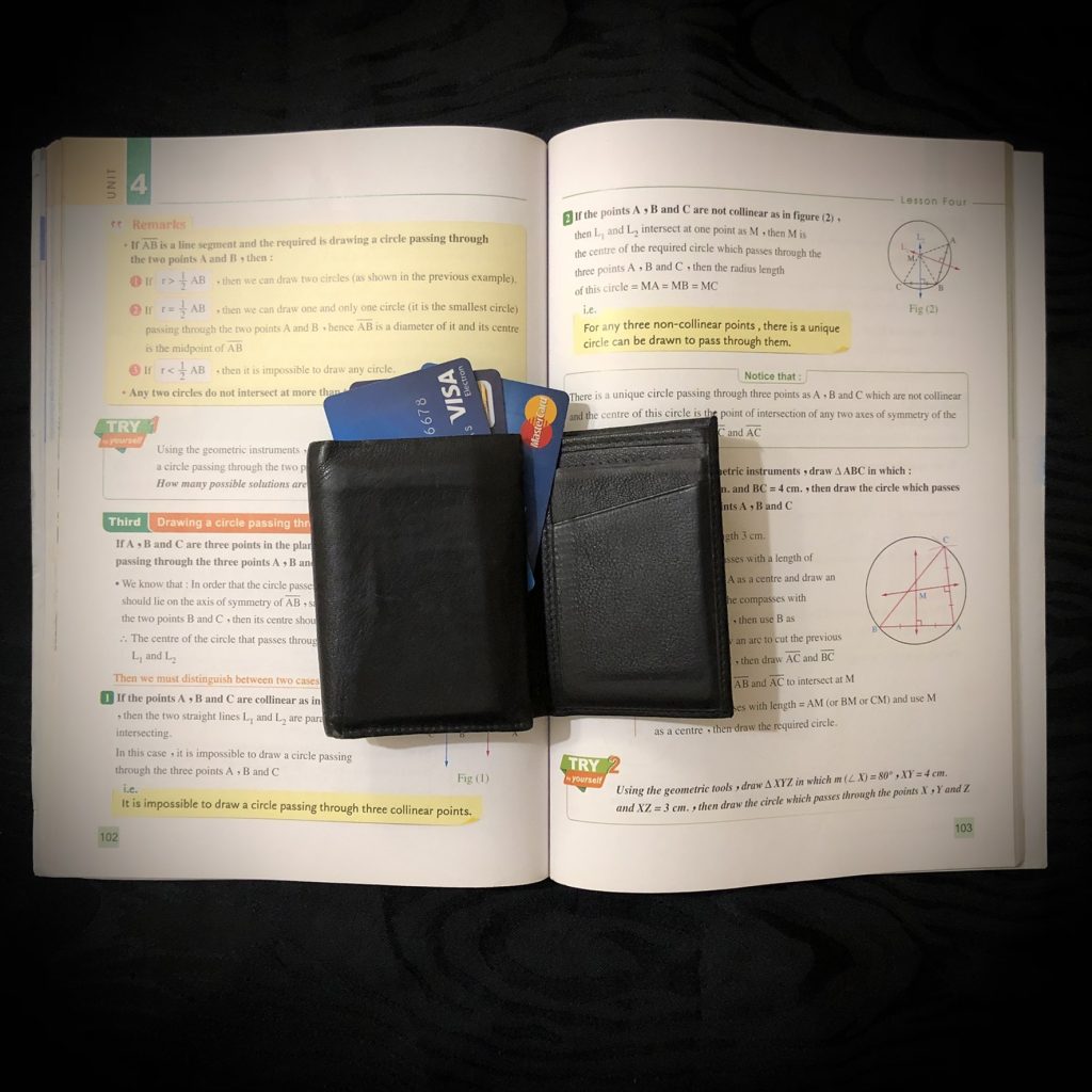 Open textbook with a wallet and cards partially inside it