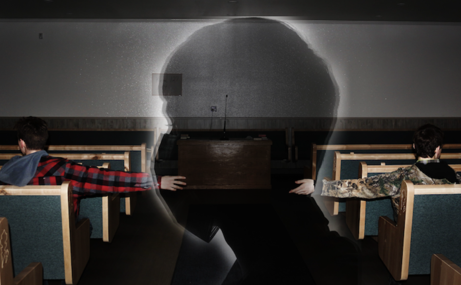 Photo of rows of seats. On each isle sits a person each for the other, looking away from one another. Overlaid is the shadow of a person wearing a mask