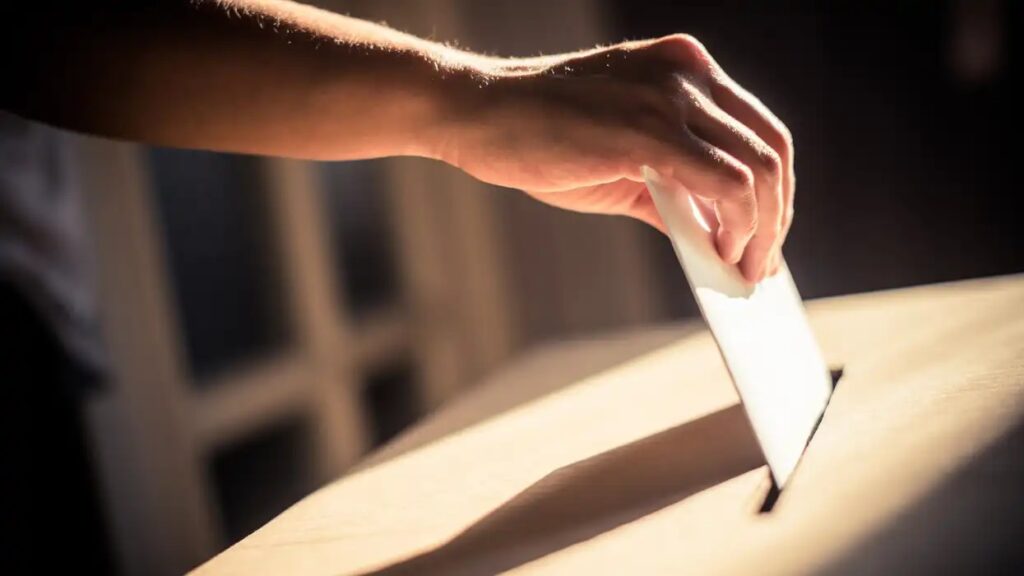 a person casting a ballot in a ballot box